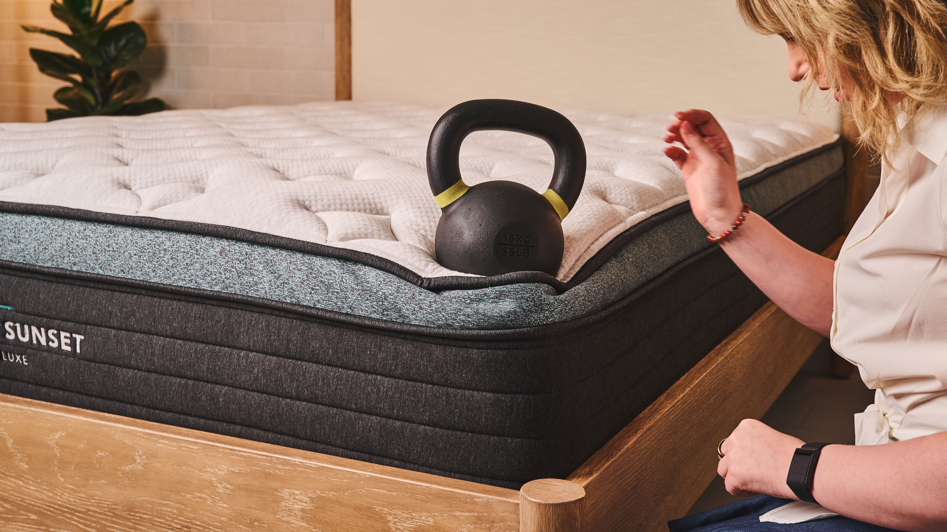 Our lead tester places a kettlebell weight on the corner of the Helix Sunset Luxe mattress to test the edge support