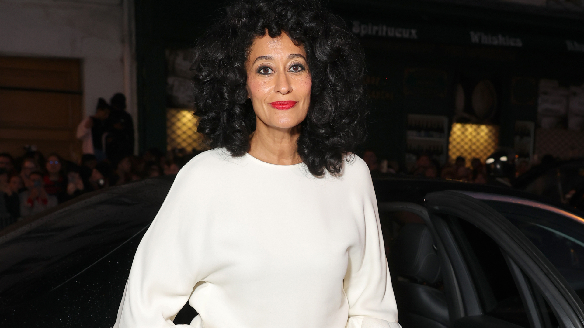 Tracee Ellis Ross with curled hair. She is wearing a white sweater and red lipstick.
