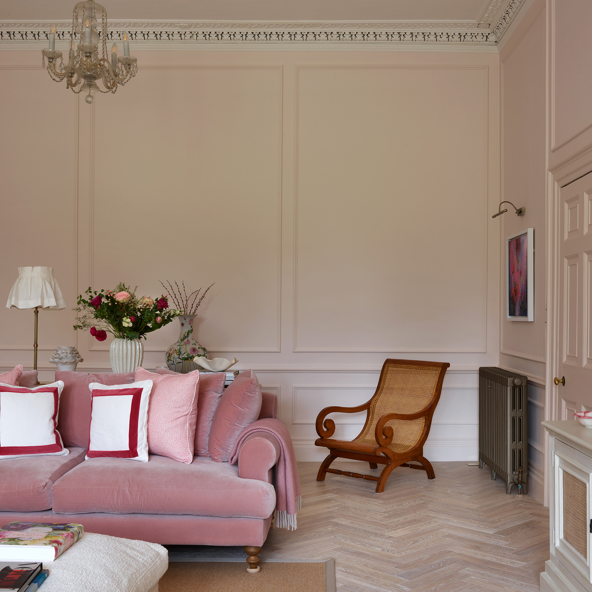 pink living room with wall panelling, ornate coving, pink velvet sofa and parquet flooring