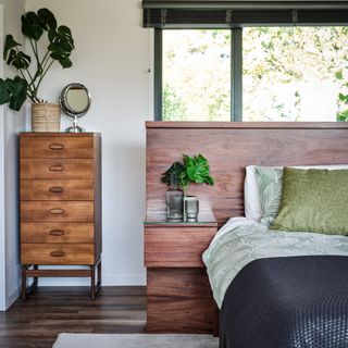 Natural headboard, bedside table, and dresser with neutral coloured green bedding