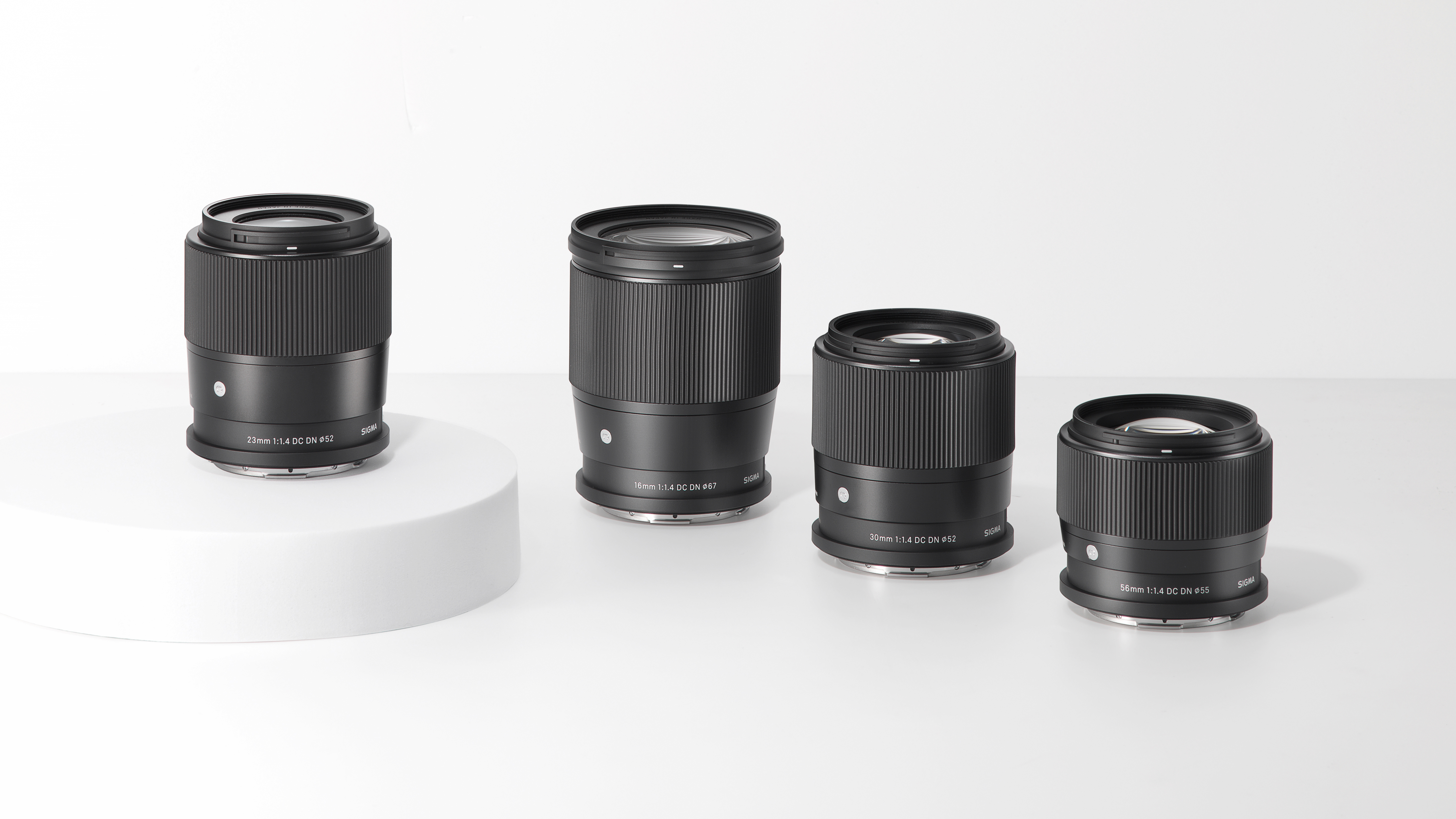 Four Sigma lenses standing on a white table