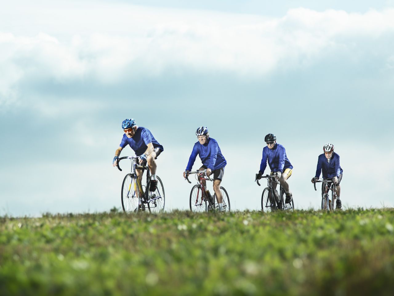 Four senior men ride road bikes