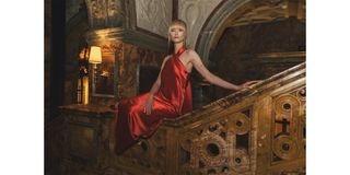 Jessica Madsen sits on staircase in red satin halter dress by Galvan.