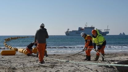 Employees install a subsea cable on the ocean shore in southern France. 