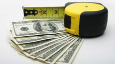 A measuring tape measures a fan of $20 bills.