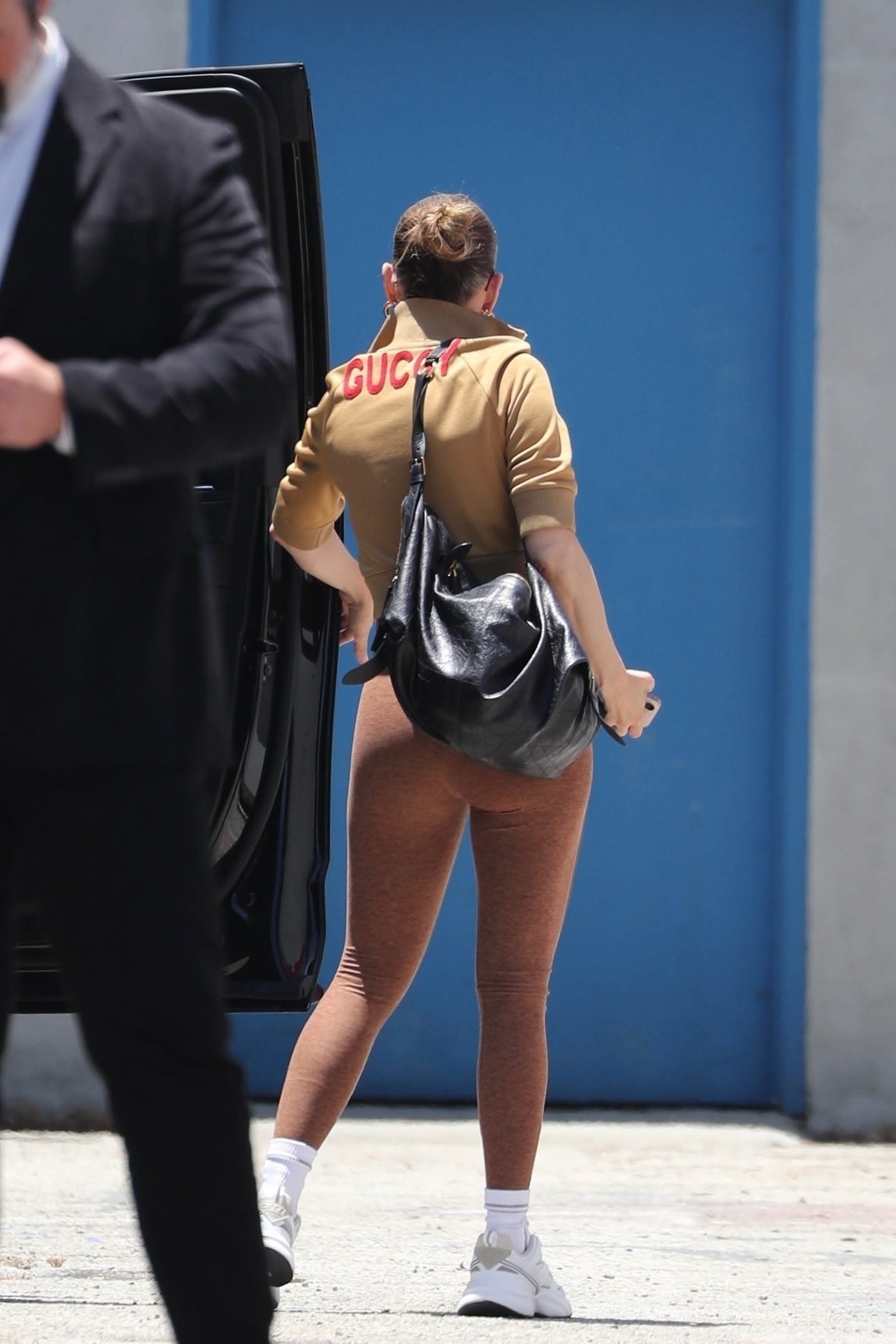 Jennifer Lopez styles white chunky sneakers with a Gucci jacket and a Dior bag