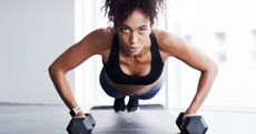 A woman performing a devil press with a pair of dumbbells 