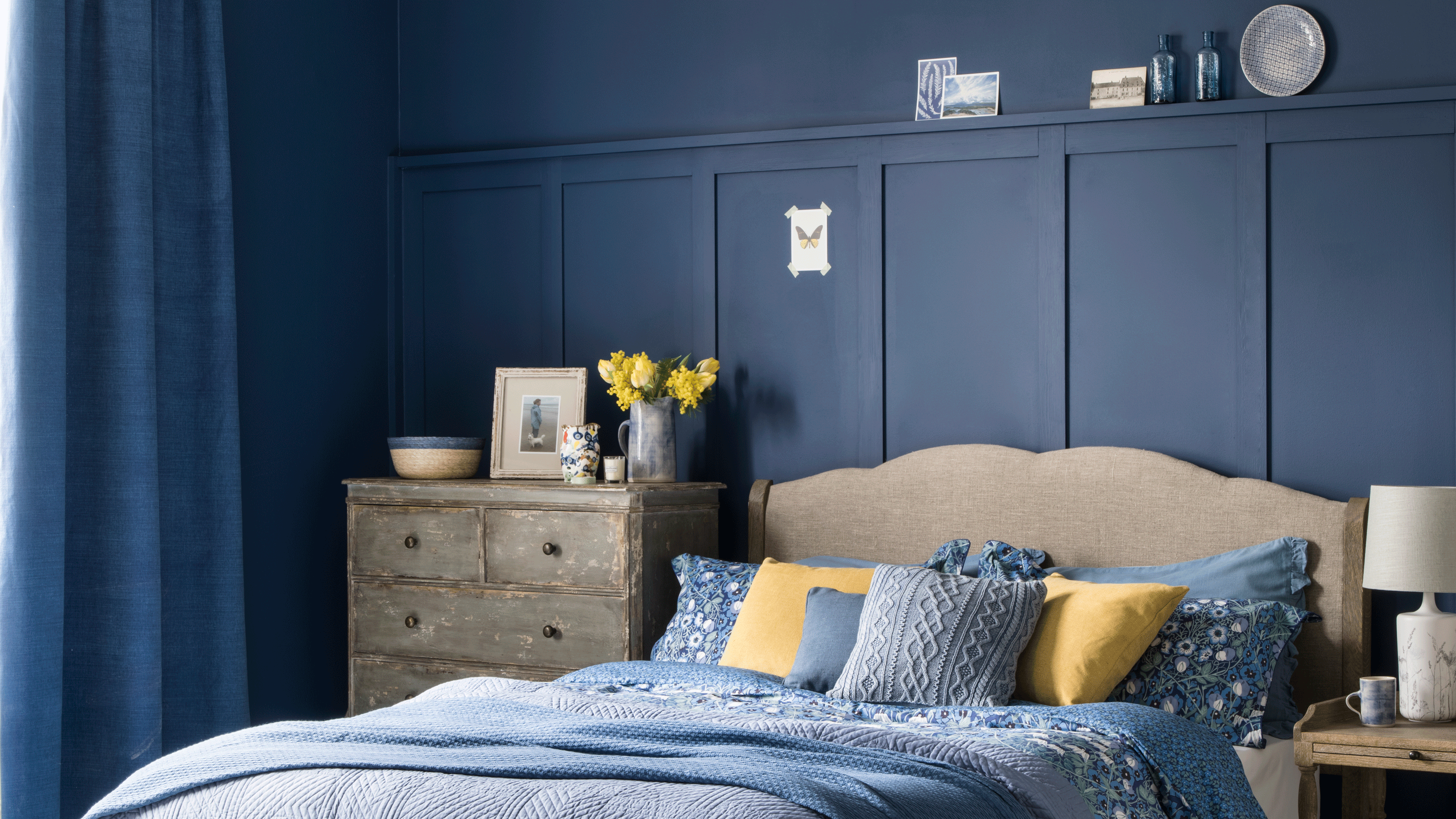Navy blue bedroom with wooden bed and wooden chest of drawers