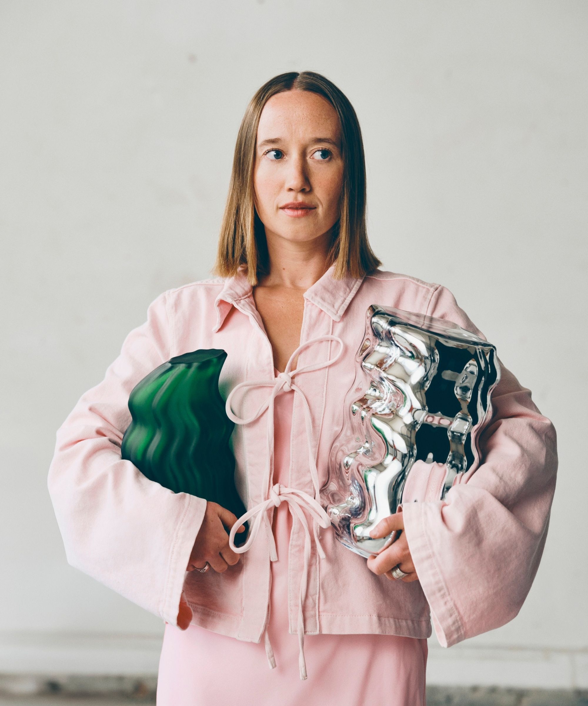 girl in pink shirt and skirt holding a green and silver sculptural object