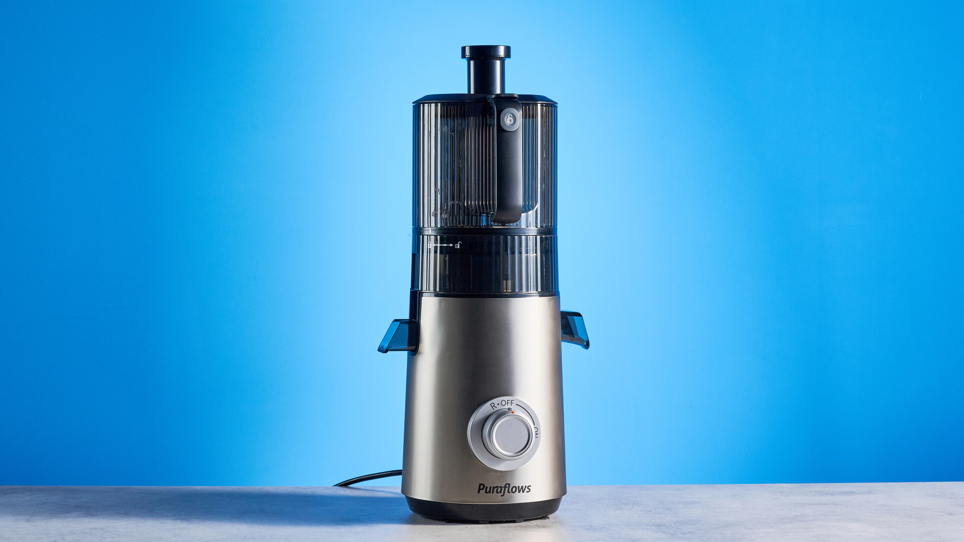Puraflows Auramist Cold Press Juicer and accessories photographed in front of a blue background