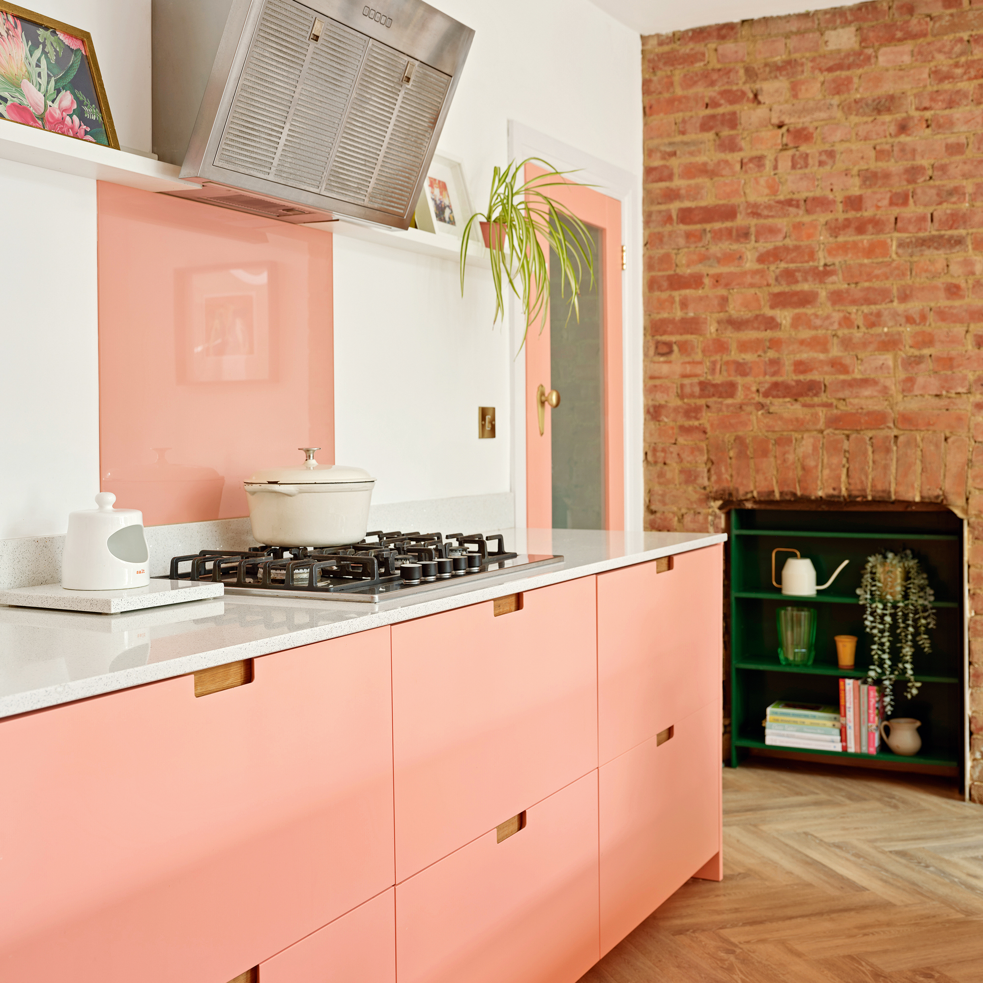 modern pink kitchen cabinets and matching painted glazed door, a gas hob, with pink matching splashback, and an exposed brick chimney breast
