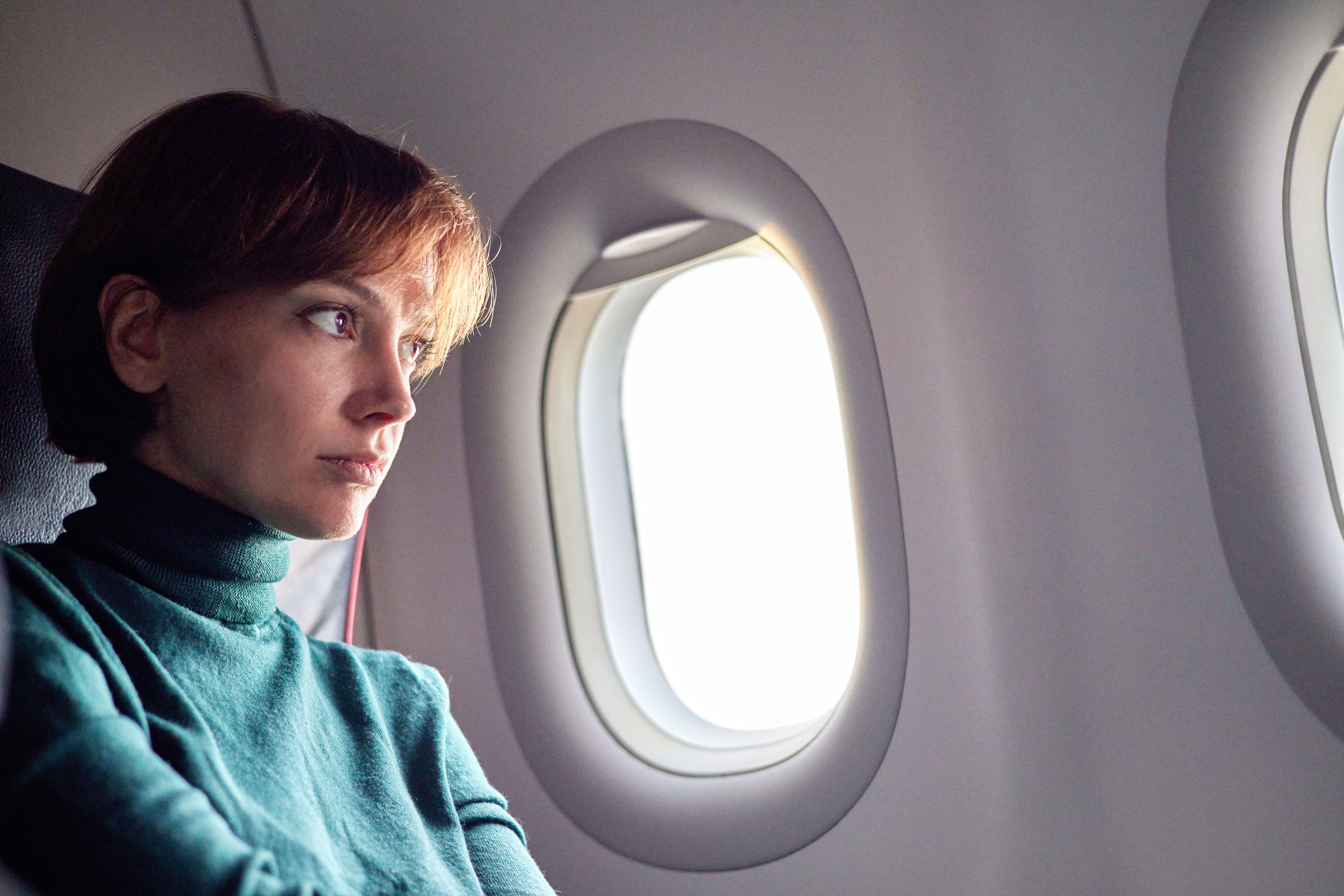A woman sits awake on an airplane looking unhappy.