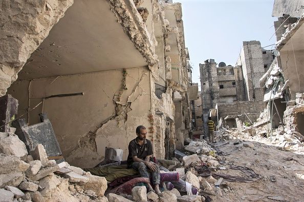 A man sits in rubble in Aleppo, Syria.