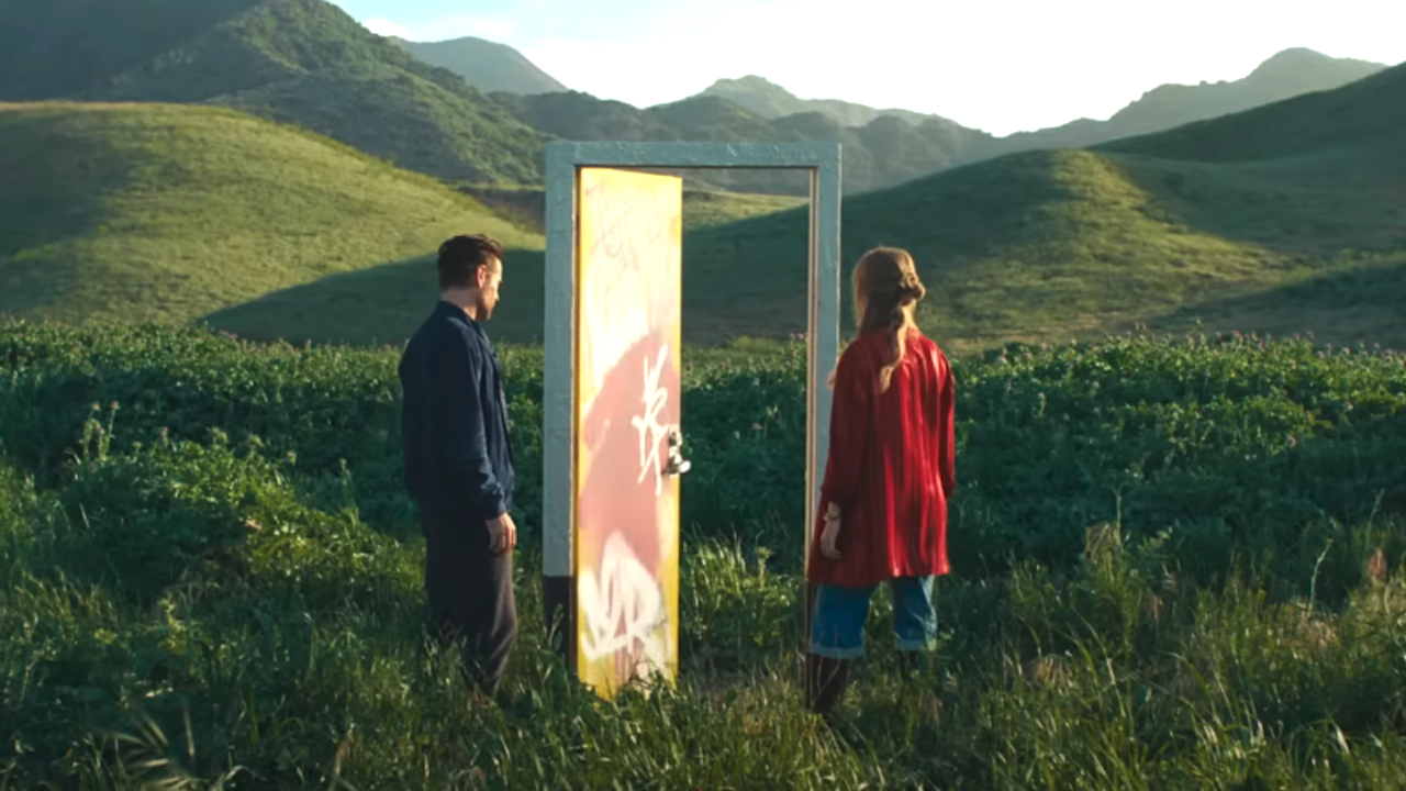 Colin Farrell and Margot Robbie standing by a door in a middle of a hilly countryside in A Big Bold Beautiful Journey still