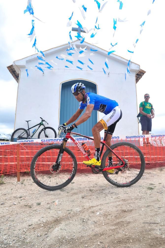 A rider passes by a church atop the hill