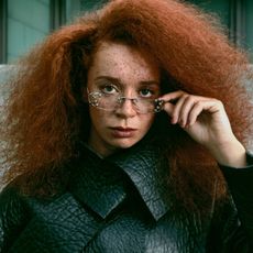 Photo of Erin Kellyman for the Fall Ones to Watch portfolio. She is pictured wearing a pebbled Prada leather jacket and metal-accented glasses.
