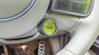 Close-up of yellow boost button on a cream leather steering wheel