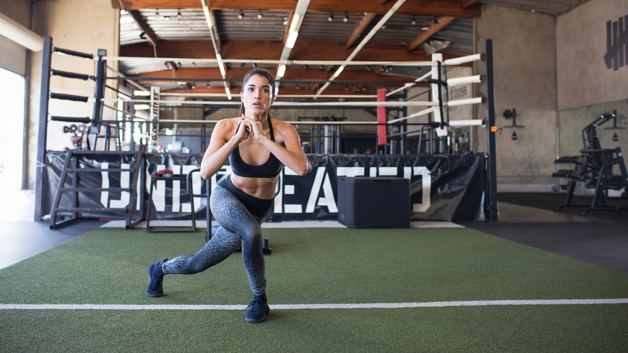 Woman performing curtsy lunge in gym