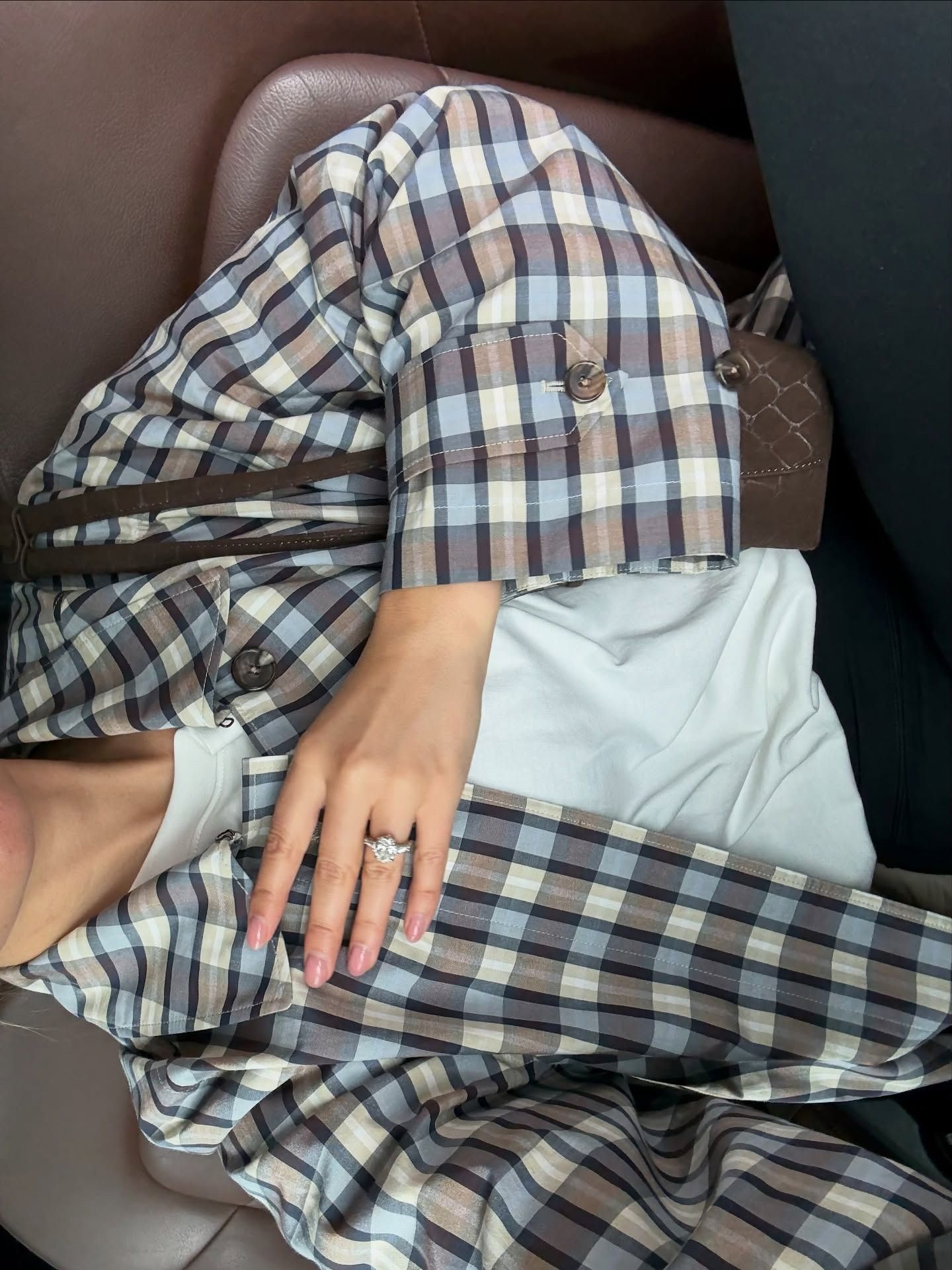 A woman wears a plaid coat and white short-sleeve shirt.