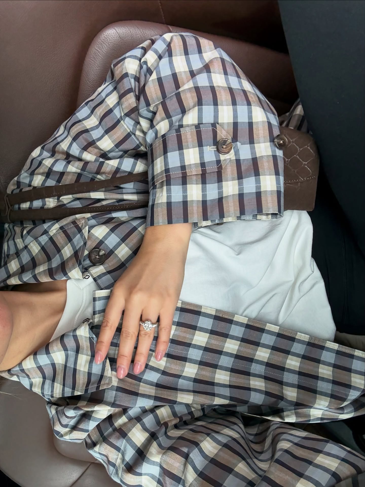 A woman wears a plaid coat and white short-sleeve shirt.