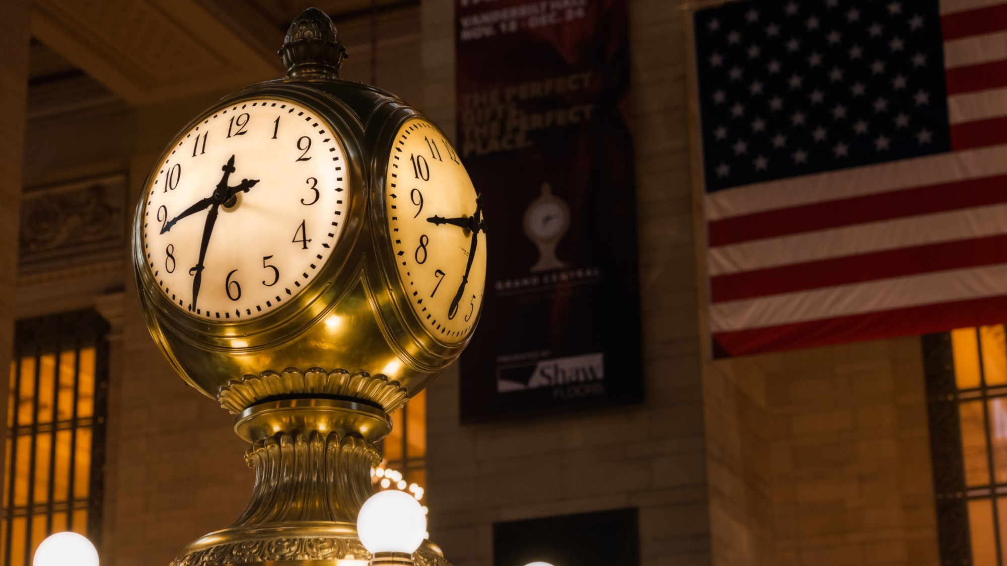 Clock in Grand Central Station in Manhattan, New York City, with American flag in the background