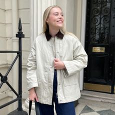 Women wears beige jacket, blue jeans