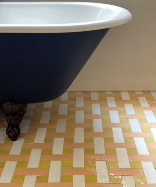 vintage bathroom with a freestanding bathtub and pink and yellow and white weaved floor tiles