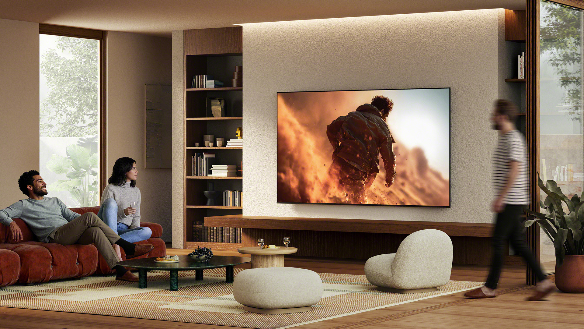 Lifestyle image showing a wall-mounted Sony Bravia 7 II True RGB TV with people around it in a living room environment
