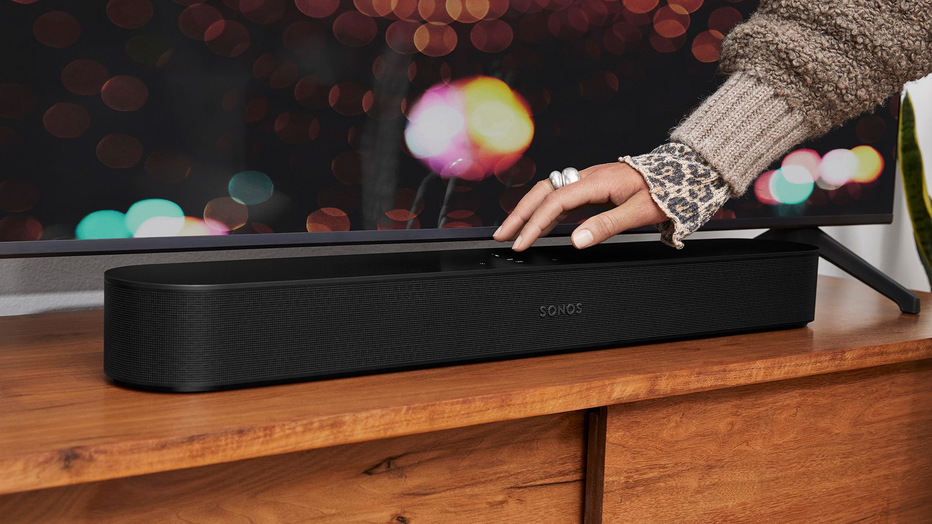 Sonos Beam 2 soundbar in black being turned off by a woman