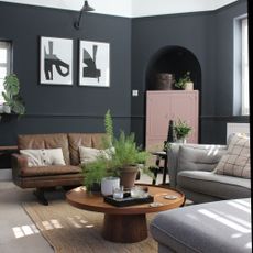 Black living room with retro leather sofa, grey chaise sofa and pink painted cabinet