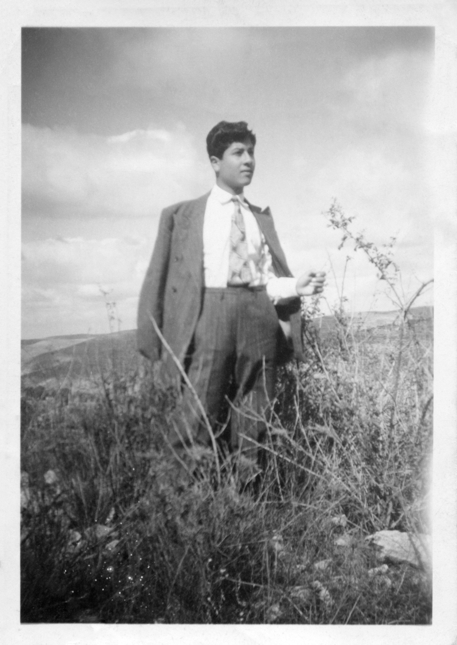 an old black and white photo of author elena dudum's grandfather wearing a suit and standing in a field in palestine