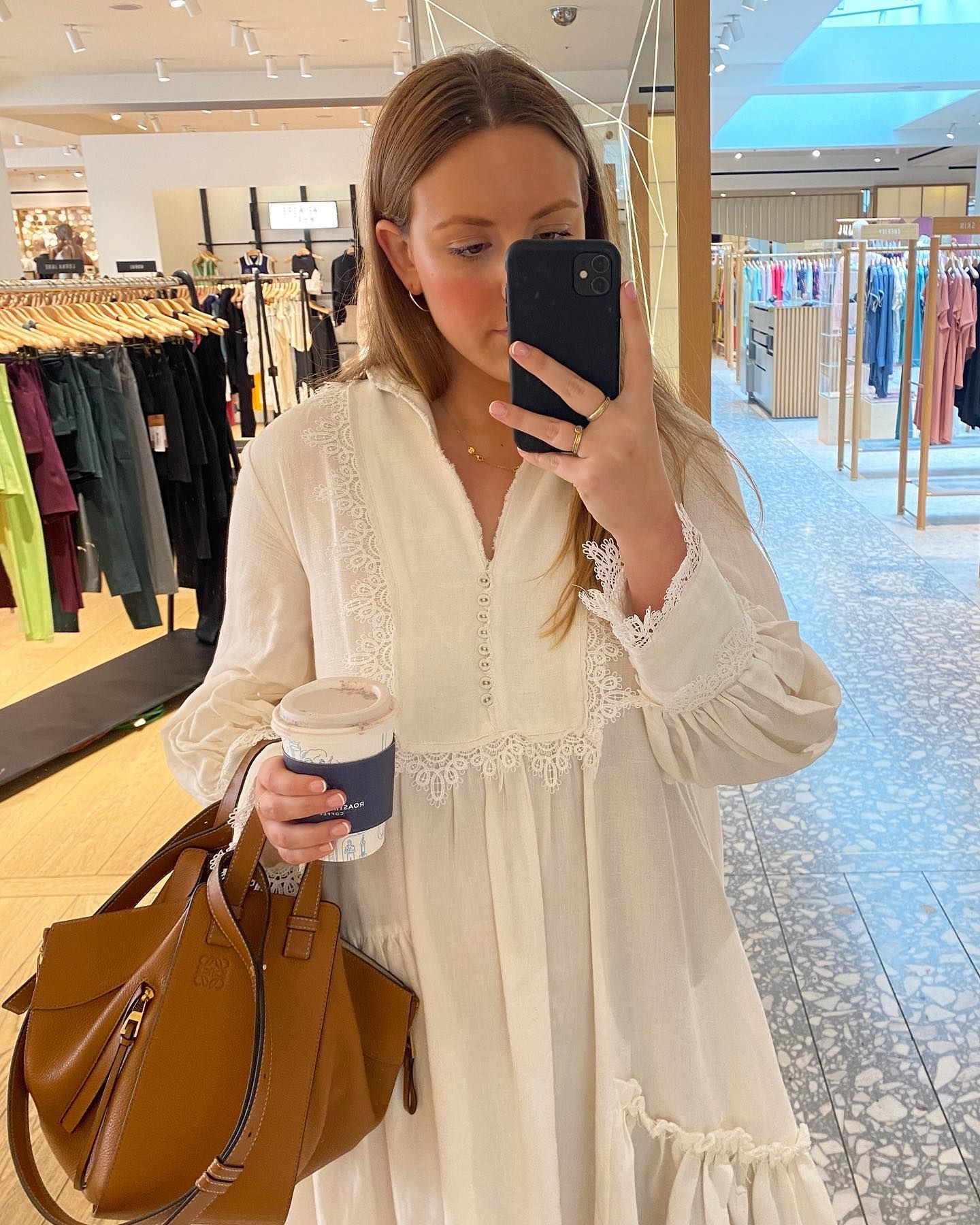 Poppy wears a white dress and carries beige Loewe bag