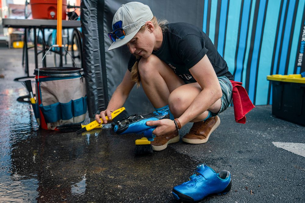 Brenna Wrye-Simpson cleaning bike shoes in the mechanic pits