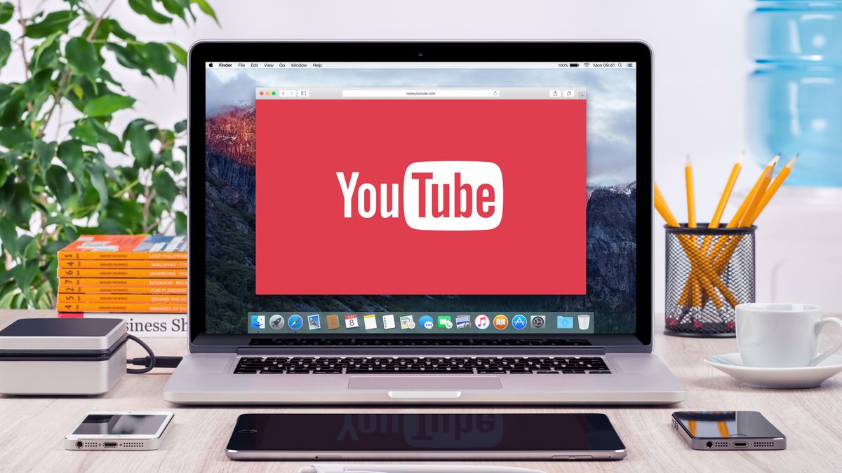 YouTube&#039;s logo is in a window on a MacBook on a desk that&#039;s very neatly arranged