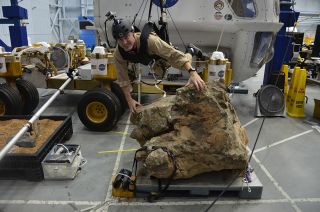 Marc Reagan is suspended above a boulder on a simulated asteroid inside NASA Active Response Gravity Offload System, or ARGOS, at Johnson Space Center in Houston, Aug. 30, 2012