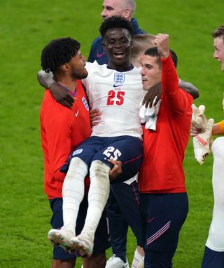 Tyrone Mings and Conor Coady carry Bukayo Saka as they celebrate victory over Denmark