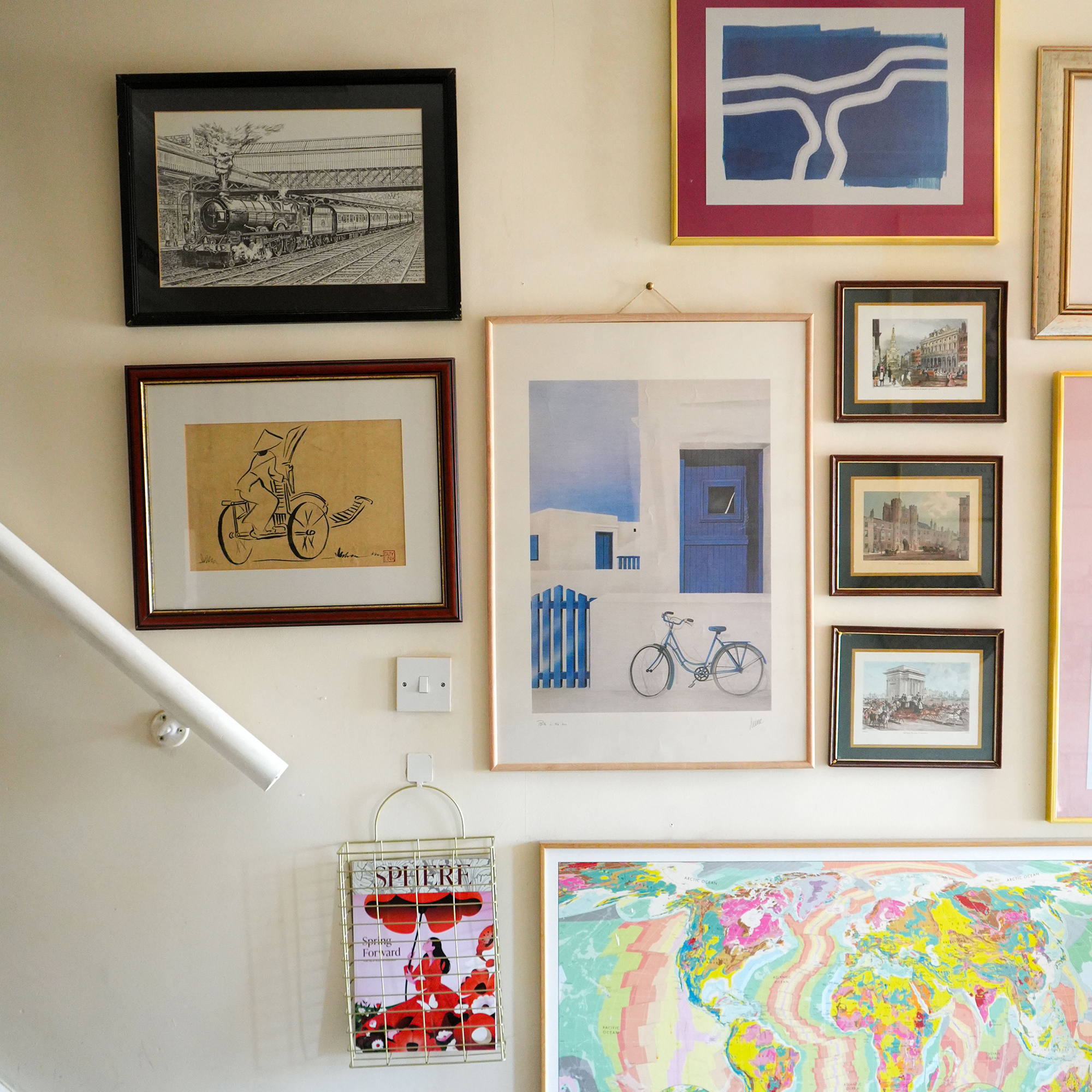 gallery wall showing different sized framed artwork held up by upholstery pins on a magnolia hallway wall