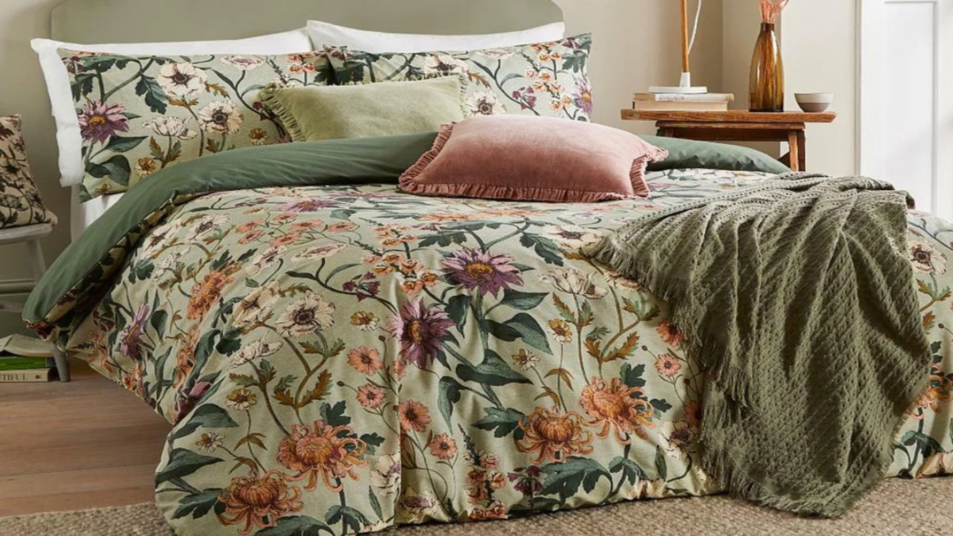 A taupe bedroom with green headboard dressed with green bedding covered in a floral print