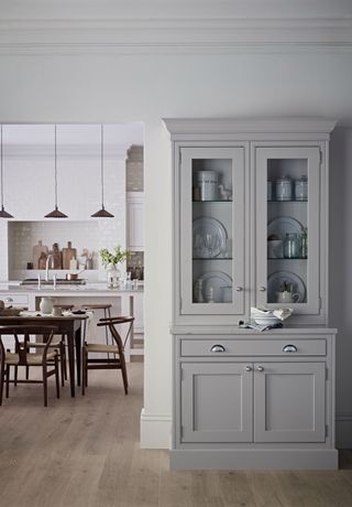 An open-plan kitchen space with grey dresser cabinet and trio of pendant lights over kitchen dining table