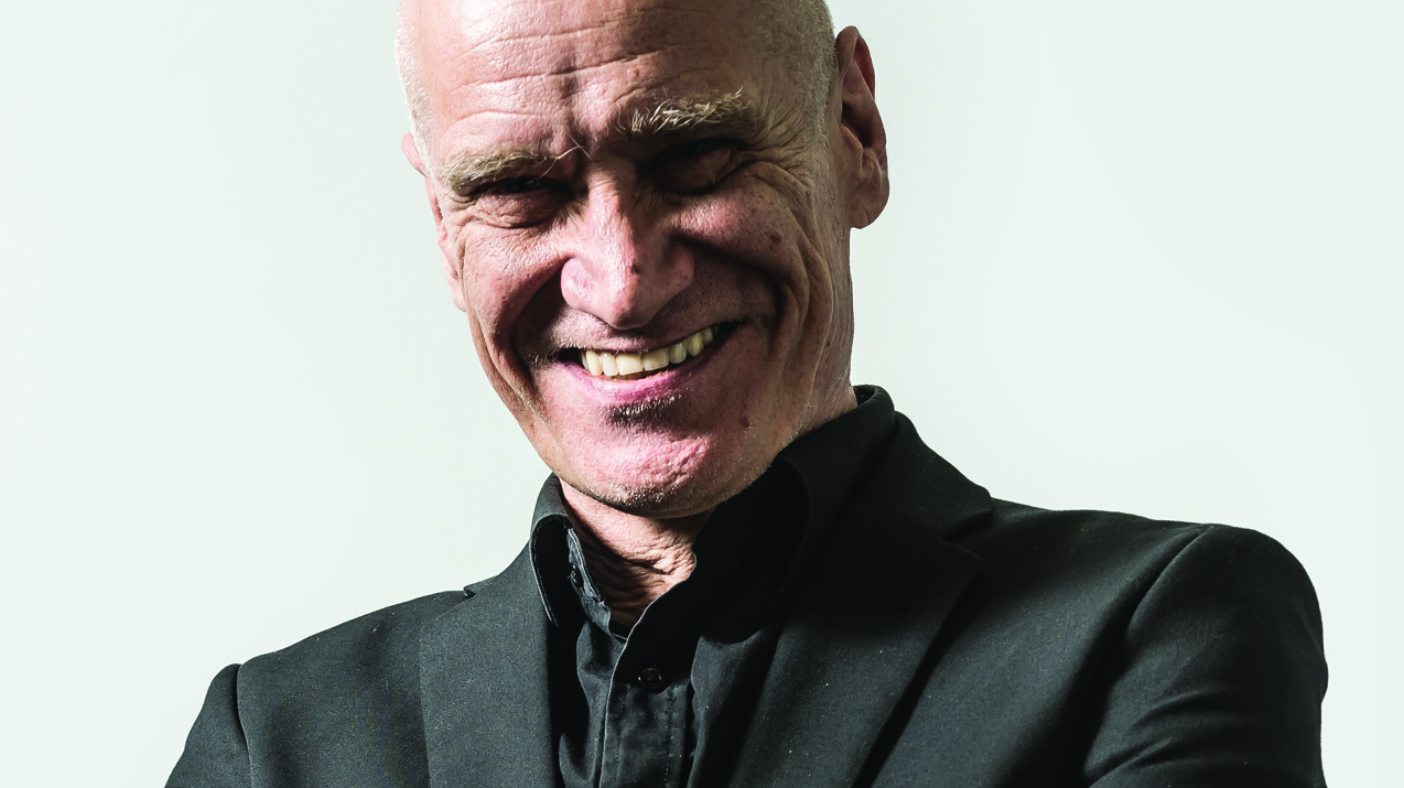 Wilko Johnson looking at the camera and smiling.