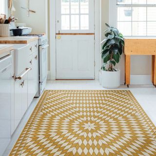 A yellow and white sunburst vinyl rug sits in a white kitchen