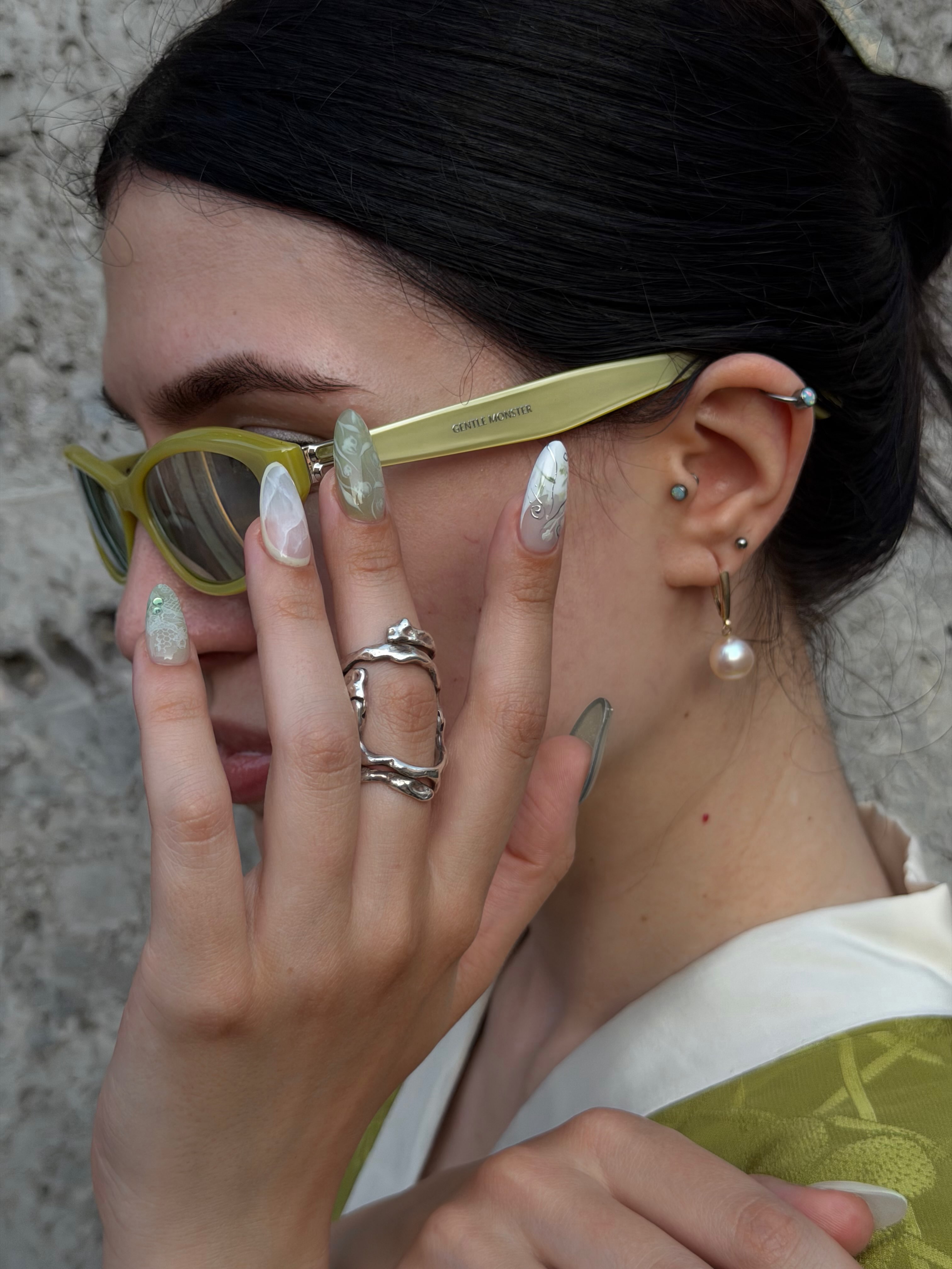 An image of a woman wearing a mismatched green manicure.
