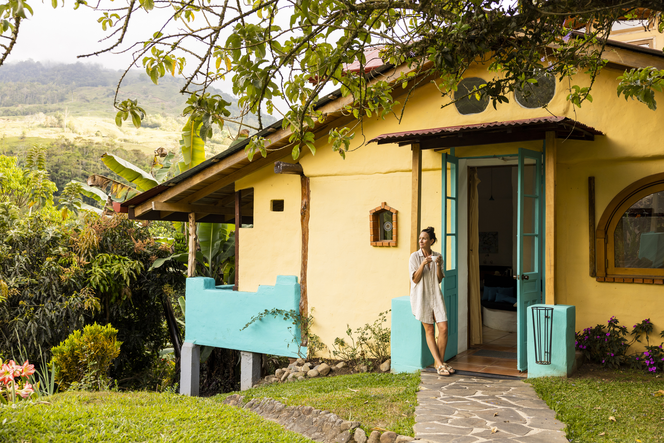 A woman enjoying a cup of coffee at her cottage in the mountains of San Jose, Costa Rica.