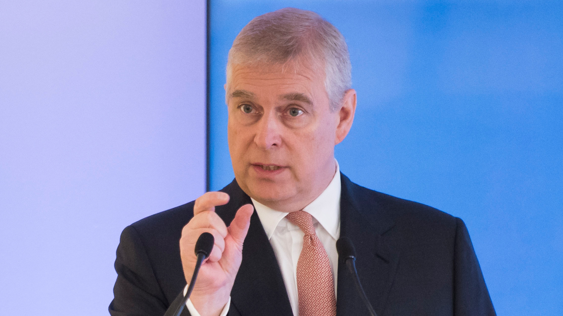 Ex-Prince Andrew gives a talk in 2017 while wearing a black suit, white shirt, and red tie
