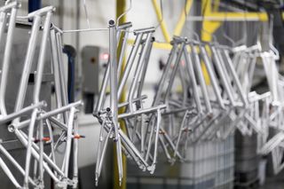 Bike frames hang in a factory ready to be painted