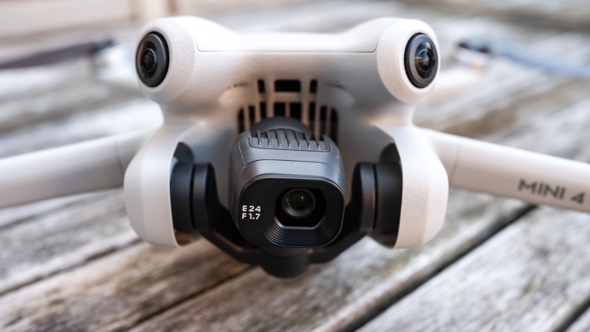 Close-up of the black camera on the front of a white DJI Mini 4 Pro drone.