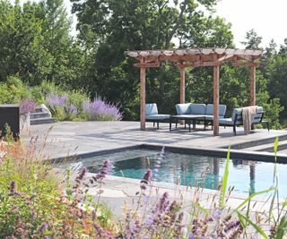 seating area with pergola by pool in garden designed by Annika Zetterman