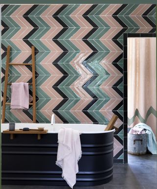 Coloured bathroom wall tiles laid diagonally against bold, dark flooring and co-ordinating fittings