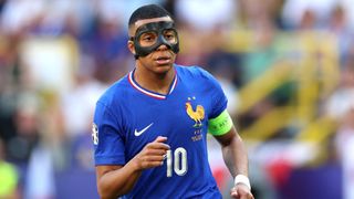 Kylian Mbappé, wearing a black protective face mask, running in France's Euro 2024 match against Austria.