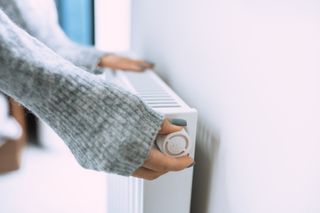 Close up of a woman adjusting the thermostat on a radiator at home